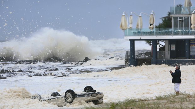 A car lies on its roof near Queensland's storm-lashed Currumbin Surf Club yesterday. 