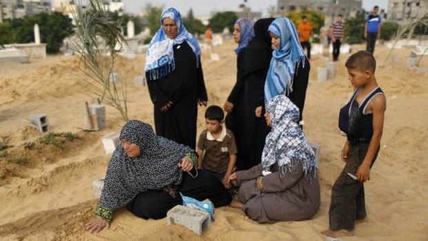 A Palestinian woman (left) at a cemetery in northern Gaza on Eid al-Fitr next to the grave of her son, who medics said was killed during the Israeli offensive.