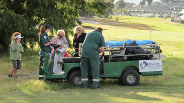 A woman is treated by paramedics after being struck in the leg by an errant shot from one of Tiger Woods's playing partners at today's Australian Masters pro-am.