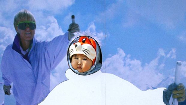 Precious Snowflakes ... a child pokes its head through a ski poster in Beijing.