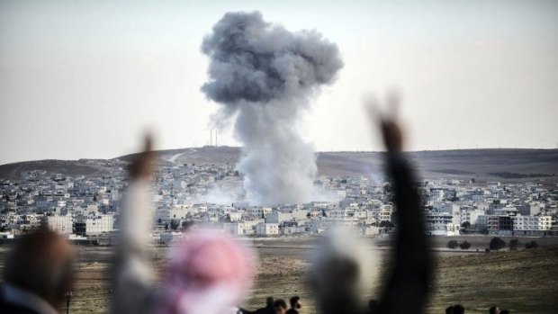 Kurds watch on from Syria as a coalition air-strike hits an IS position in Kobane.