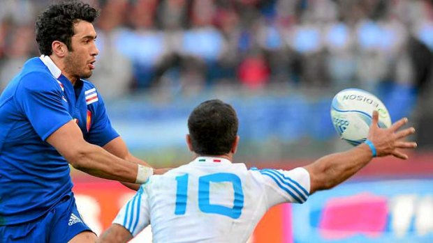 France's centre Maxime Mermoz passes the ball in front of Italy's fly-half Luciano Orquera.