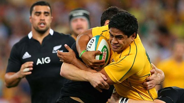 A wing and a prayer: Wallabies back Ben Tapuai is stopped in his tracks by the All Blacks defence last night.