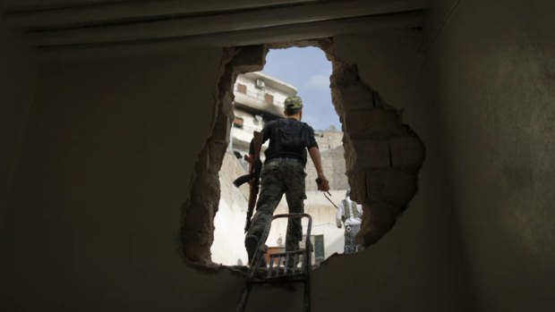 Chink of light ... a Free Syria Army fighter walks through a hole in the wall during fighting in Aleppo.