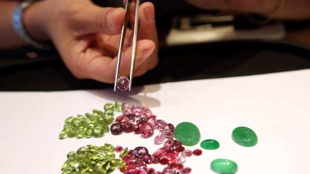 An employee displays peridot, left, ruby, centre, and green jade stones at the Myanmar VES Joint Venture showroom in Yangon, Myanmar, in 2013.