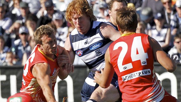On the boot: Geelong captain Cameron Ling squeezes a kick between Suns midfielders Sam Iles (left) and David Swallow.