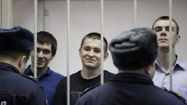 Smiling in defiance ... Defendants stand inside a holding cell during a hearing at a courthouse in Moscow. 