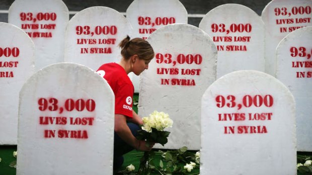An Oxfam worker in Belfast places roses among rows of gravestones symbolising the 93,00 people killed in Syria. The crisis is set to dominate talks at the G8 meeting in Belfast.