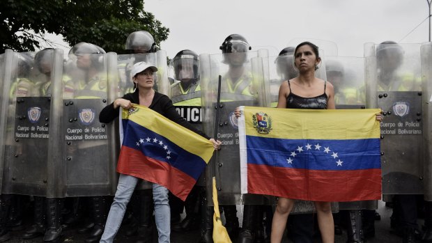Protesters hold Venezuelan Flags in front of police during an opposition march in Caracas on May 11.