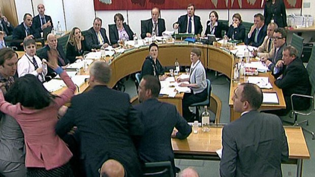 House of Commons Committee members and Rupert Murdoch's wife, Wendi Deng, in pink, react as Jonathan May-Bowles tries to throw a paper plate covered in shaving foam over Mr  Murdoch.