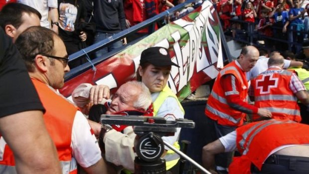 An Osasuna supporter is helped after the barrier collapsed.