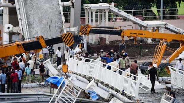 Indian workers dismantle the collapsed footbridge at the Jawaharlal Stadium.