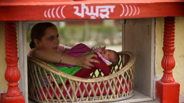 A Red Cross worker collects a baby girl left anonymously at the Red Cross offices in Amritsar, Punjab.