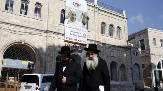 Two Ultra Orthodox Jews walk past a large poster bearing the portrait of Pope Francis hanged on the facade of the Christian Information Centre in the Old City of Jerusalem. 