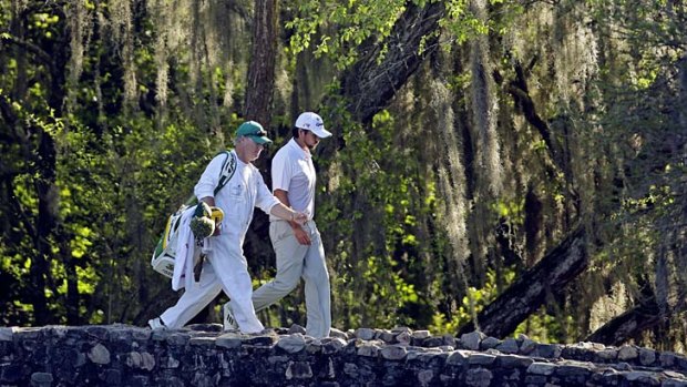 On the brink: Australia's Jason Day walks across Nelson Bridge at Augusta National with caddie Colin Swatton during the third round of the Masters on Saturday.