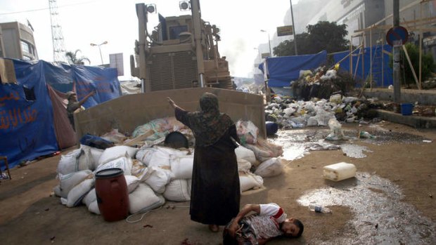 No-go zone: a woman stands between a military bulldozer and a wounded protester near Rabaa al-Adawiya mosque.