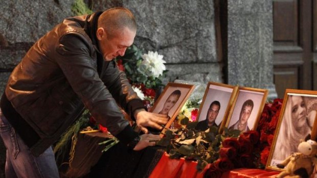 A man grieves near the portraits of victims of suicide bombings at the main railway station in Volgograd.