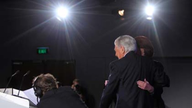 Caught out...a stagehand slips Julia Gillard's notes on to the lectern ahead of her speech at the Labor campaign launch.