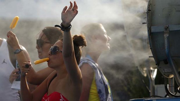 Spectators cool off with popsicles in front of a misting fan at the Australian Open.