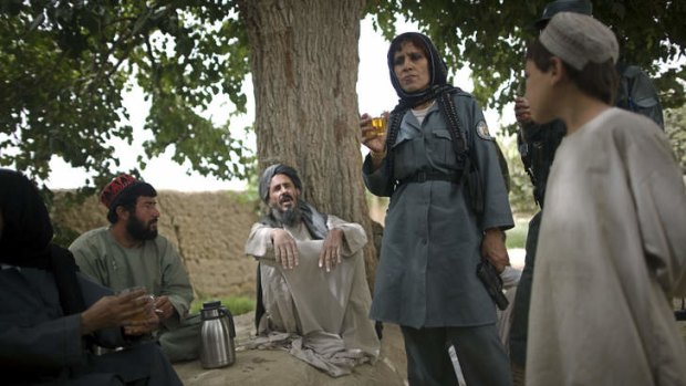 An Afghan policewoman drinks tea with local villagers in Samir Kalacha in 2010.