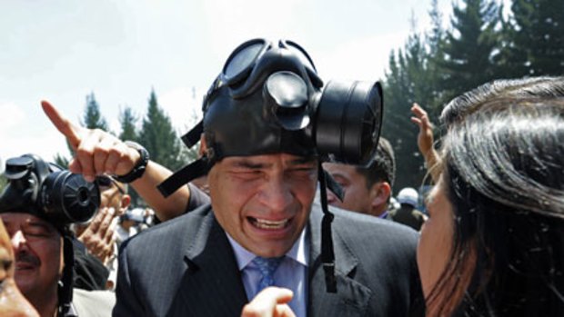 Man behind the mask ... Rafael Correa runs away from tear gas during a police protest against his veto of a law that would have given them better benefits.