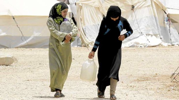 Syrian refugees carry water containers through the northern Jordanian Zaatari refugee camp, which is now equal in size to Jordan's fifth-largest city.