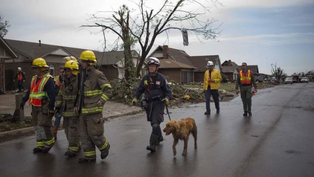 Rescue workers use a canine while searching house-to-house for survivors in a neighborhood left devastated by a tornado in Moore, Oklahoma,