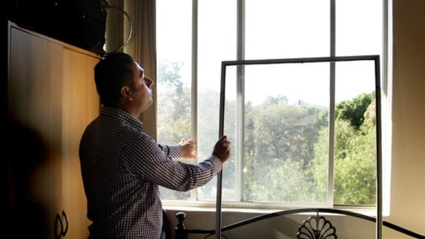 Sazzad Afaz at the  window in his unit from which the three-year-old fell and died.