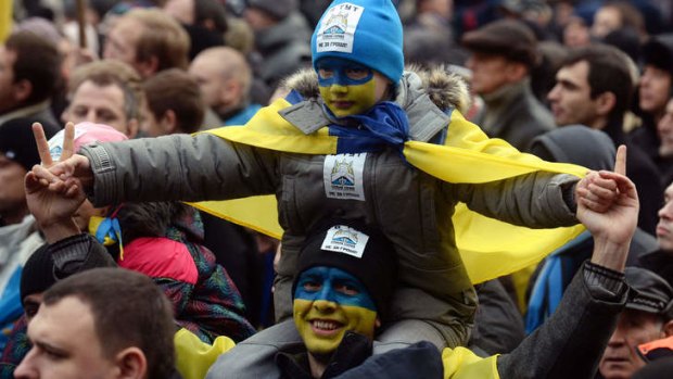 A Ukrainian demonstrator and his son, with their faces painted in the colours of the national flag, attend a pro-EU opposition rally at Independence Square in Kiev on December 1, 2013.