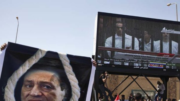 Top billing ... opponents watch the televised trial of the deposed president Hosni Mubarak and family members in Cairo.