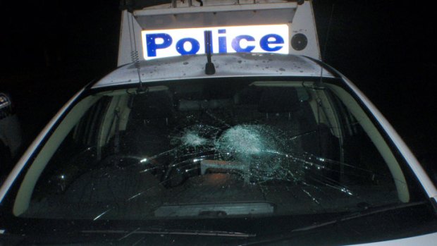 A police car's front windshield is smashed by rocks and bottles thrown by teen partygoers.
