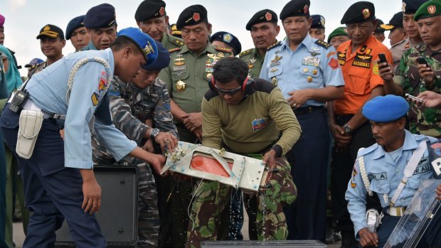 Indonesian officers move the retrieved flight data recorder of the AirAsia flight QZ8501.