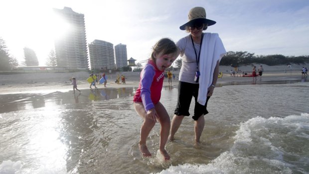 Charlotte Gardiner, 5, with grandmother Marilyn Gardiner, from Woollahra, jumps waves in the shallow water as lifeguards close Southport Beach due to dangerous surf.