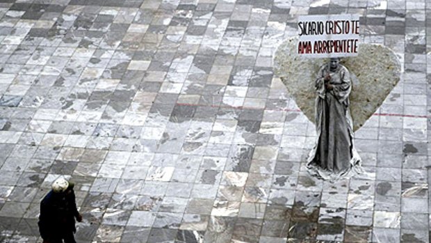 A woman dressed as an angel in a Ciudad Juarez square holds a sign that reads, ''Hitman, Christ loves you, repent.''