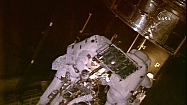 In this image obtained from NASA video, astronaut Mike Massimino, right, and Mike Good are on a fourth space walk to service the Hubble space telescope.
