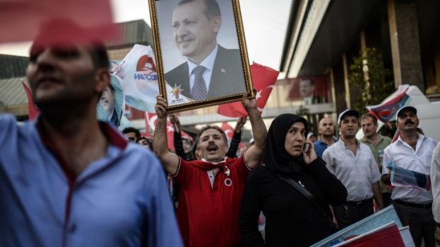 Turkish people hold a picture of Turkish Prime Minister Recep Tayyip Erdogan and flags as they celebrate after Erdogan was on course for a crushing first-round victory in presidential elections