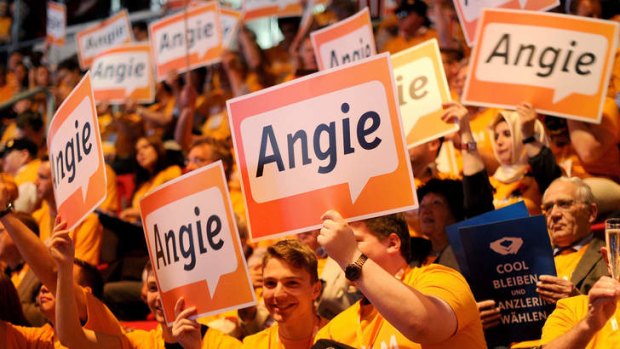 Expected victory: Supporters of Angela Merkel wave posters on Sunday in Dusseldorf.