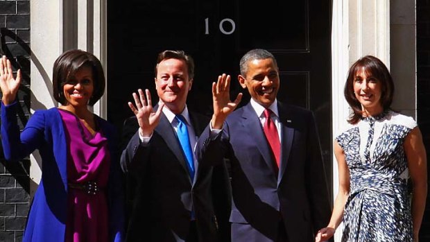 Michelle Obama, left, wore a fuchsia 1950s-inspired dress with a blue overcoat and matching kitten heels when she met British Prime Minister David Cameron and his wife Samantha.