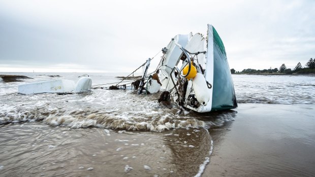 A smashed boat lies on a Devonport beach.