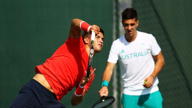 Thanasi Kokkinakis, right, looks on as Borna Coric of Croatia serves during practice at the Olympic Tennis Centre.