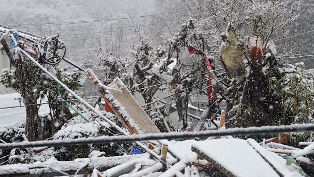 Rubble and people's personal items stuck in bushes are covered in snow in Kamaishi .