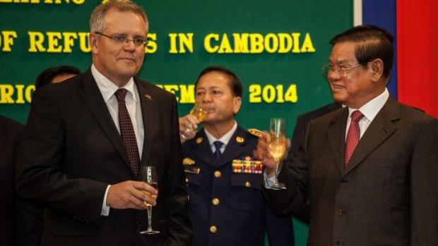 Australian Immigration Minister Scott Morrison and Cambodian Interior Minister Sar Kheng hold a flute of champagne after signing a deal to resettle refugees from Australia to Cambodia.