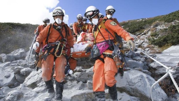 Firefighters carry a hiker trapped in the summit area of Mount Ontake during Saturday's initial eruption during rescue operations in central Japan.