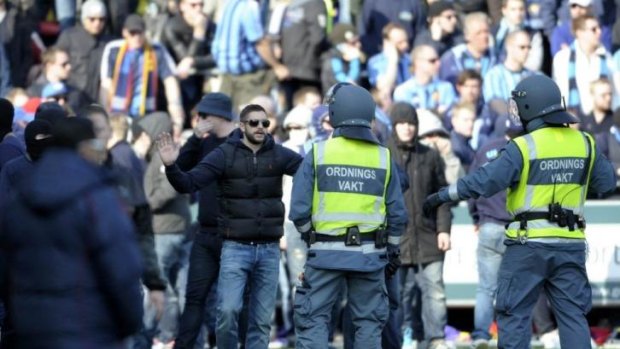 Security personnel try to control supporters of Stockholm club Djurgarden who stormed the pitch after hearing news of the death of a fellow supporter.