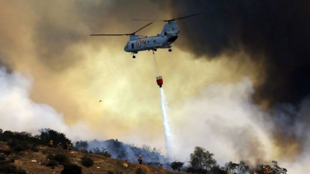 A US military helicopter drops water on a fire in San Marcos.