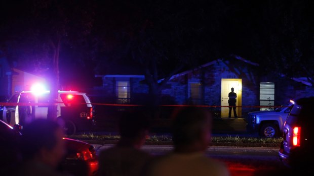 Onlookers watch police at the shooting at a home in Plano on Sunday night.