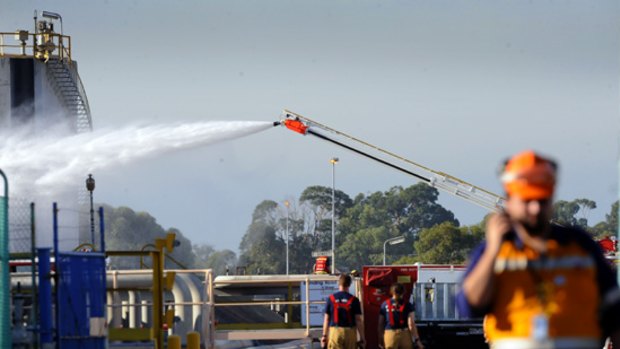 Firefighters pour water onto the side of the  leaking fuel tank at Mobil's Altona refinery.