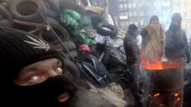 Anti-government protesters warm themself at a barricade in Kiev on January 30. A bill passed by Ukraine's parliament to amnesty arrested activists gives protesters a 15-day deadline to leave occupied streets and administrative buildings otherwise it will not be implemented. 
