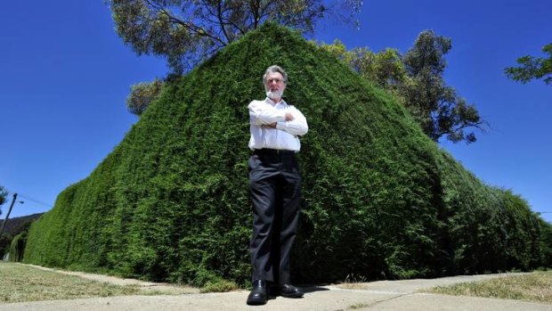 Leon Arundell of the North Canberra Community Council is forced to walk on the grass due to the over grown hedge that covers the footpath on Chapman Street in Braddon.