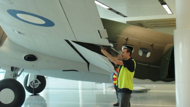 Australian War Memorial conservator Jamie Croker (front) and colleagues reassemble a World War II bomber at Canberra Airport.